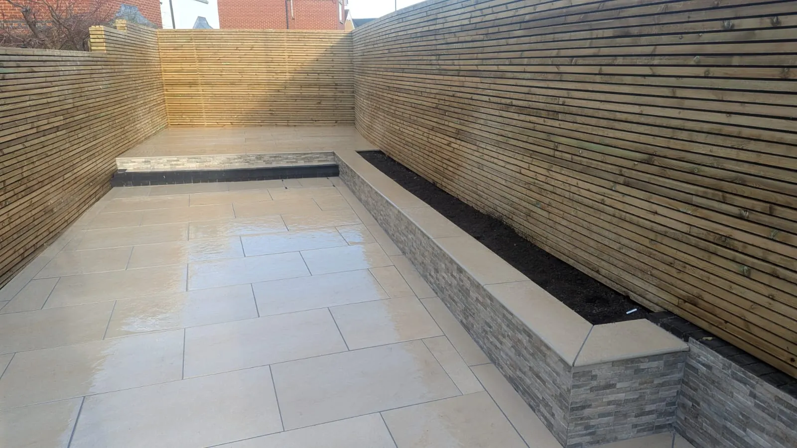 Sandstone patio with raised planters and fencing