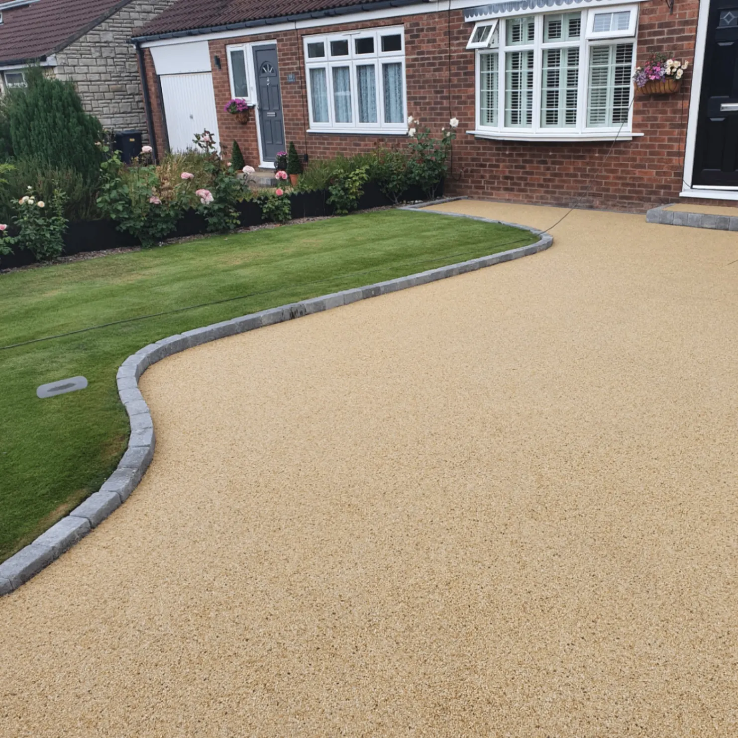 Golden resin driveway with curved lawn edging
