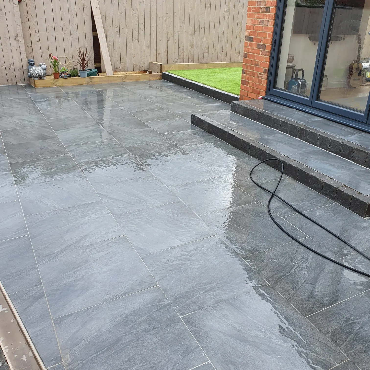 Grey patio with steps and raised lawn